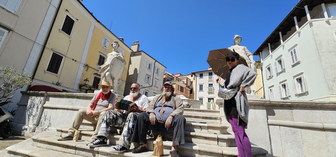 Na stopnišču vodnjaka Prvomajskega trga v Piranu sedijo trije klošarji: Boris Cavazza, Vinci Vogue Anžlovar in Primož Pirnat. FOTO: Boris Šuligoj