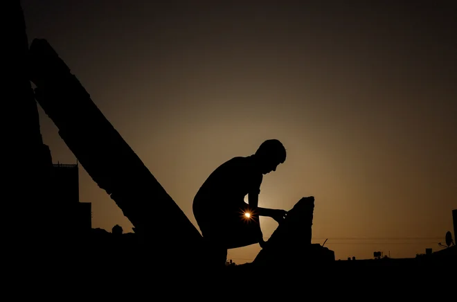 Palestinski deček stoji na ruševinah svoje hiše, ki so jo uničili izraelski letalski napadi med nedavnimi spopadi med Izraelom in Gazo. Foto: Mohammed Salem/Reuters