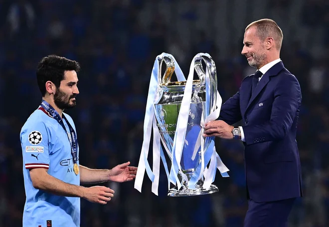 Aleksander Čeferin, predsednik Uefe, je takole izročil pokal Ilkayu Gündoganu, kapetanu Manchester Cityja. FOTO: Marco Bertorello/AFP