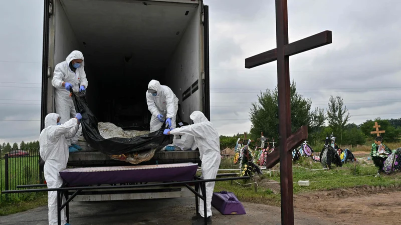 Fotografija: Delavci ukrajinskega pogrebnega podjetja na prizorišču ruskega pokola v kraju Buča. FOTO: Sergej Supinski/AFP