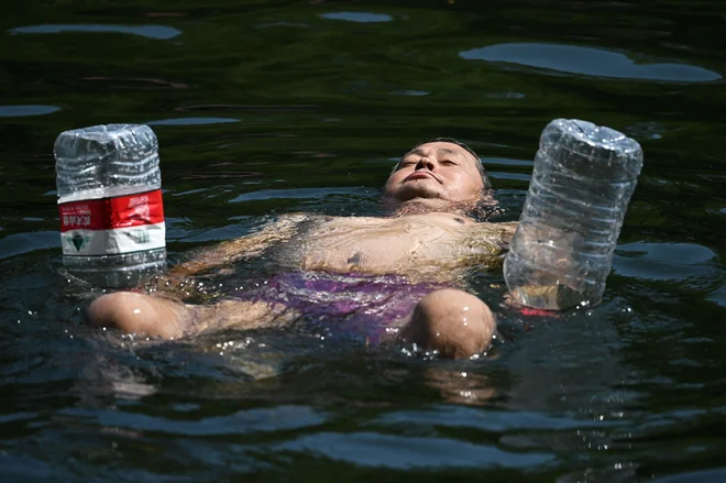 Tako Pekinžani vsaj malo ohladitve iščejo v mestnih kanalih. FOTO: Greg Baker/AFP