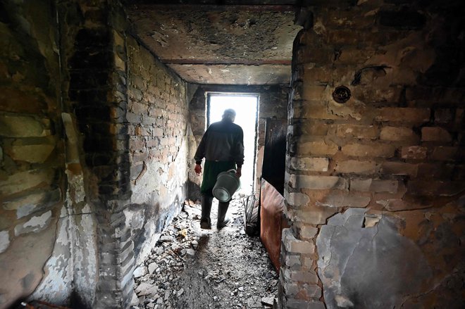 67-letni prebivalec enega od uničenih mest na vhodu v svojo stavbo. FOTO: Sergey Bobok/AFP