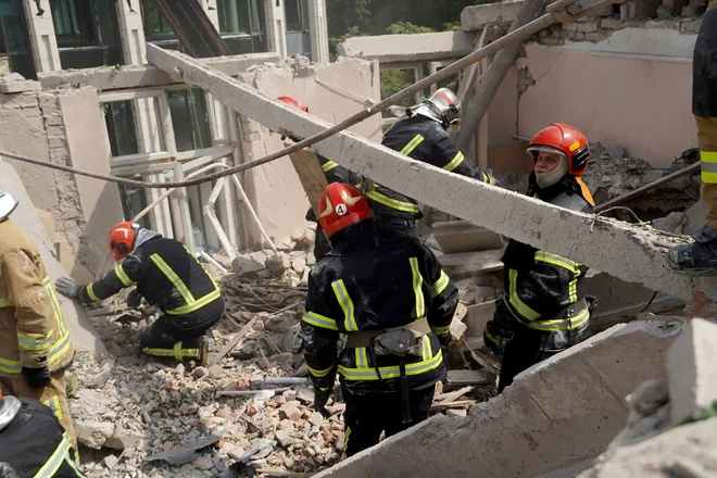 Ukrajinski reševalci med ruševinami po ruskem napadu na Lvov FOTO: Handout Afp