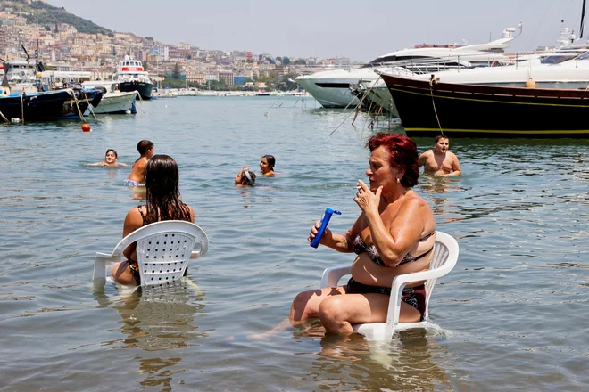 Ženska se hladi v morju v Neaplju med vročinskim valom, ki je zajel večji del Evrope. Foto: Ciro De Luca/Reuters