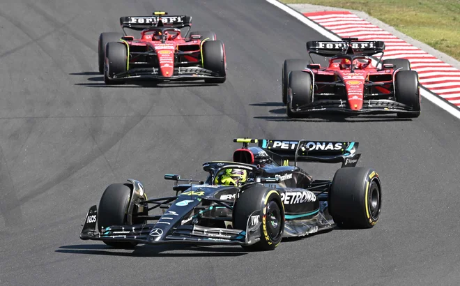 Lewis Hamilton in v ozadju voznika Ferrarija FOTO: Attila Kisbenedek/AFP