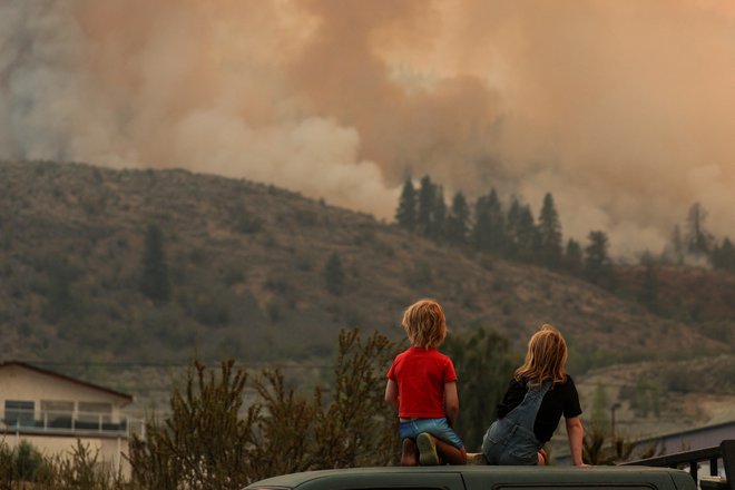 Prebivalci opazujejo gasilce, ki se borijo z ognjem na kanadsko-ameriški meji. FOTO: Jesse Winter/Reuters
