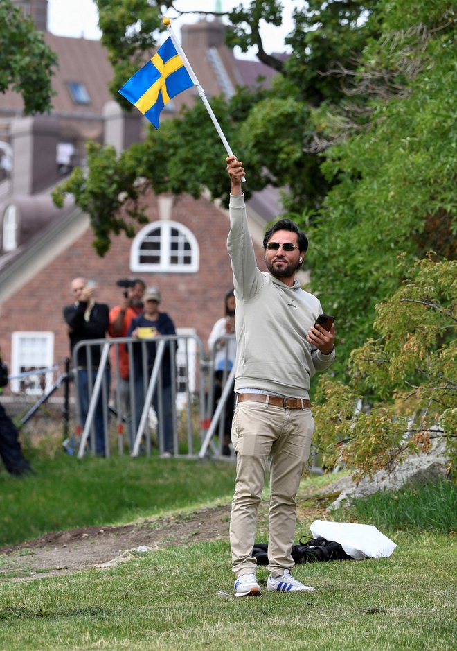 Begunec iz Iraka Salwan Momika, ki se je pripravljal na sežig korana, maha s švedsko zastavo pred iraškim veleposlaništvom v Stockholmu. FOTO: Reuters