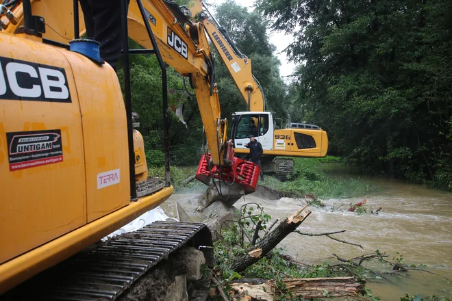 Težka mehanizacija z betonskimi bloki rešuje načeti nasip na levem bregu Mure. FOTO: Jože Pojbič 