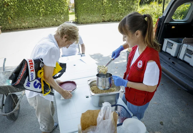 Prostovoljci Rdečega križa so med drugim razdeljevali hrano prizadetim v poplavah v Sneberju. FOTO: Jože Suhadolnik/delo