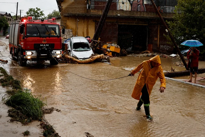Gasilec med intervencijo v poplavljenem Volosu. FOTO: Louisa Gouliamaki/Reuters