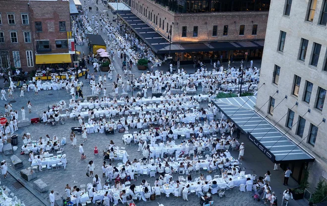Utrinek iz 11. izdaje Večerje v belem na Manhattnu v New Yorku. Legendarni popolnoma beli skrivni pop-up, katerega lokacija je razkrita nekaj ur pred dogodkom, privablja goste, ki se oblečejo v bela oblačila od glave do peta in se udeležijo kulinaričnega doživetja pod zvezdami. Letošnji dogodek je potekal v znamenitem okrožju Meatpacking. Foto: Timothy A. Clary/Afp