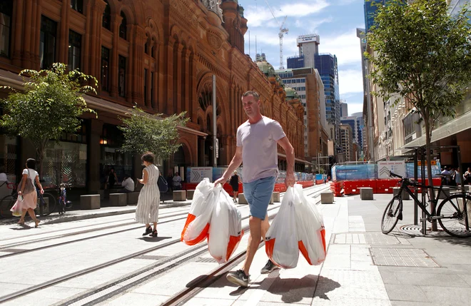 Moški na ulici Sydneyja s plastičnimi vrečkami v roki. FOTO: Daniel Munoz/Reuters