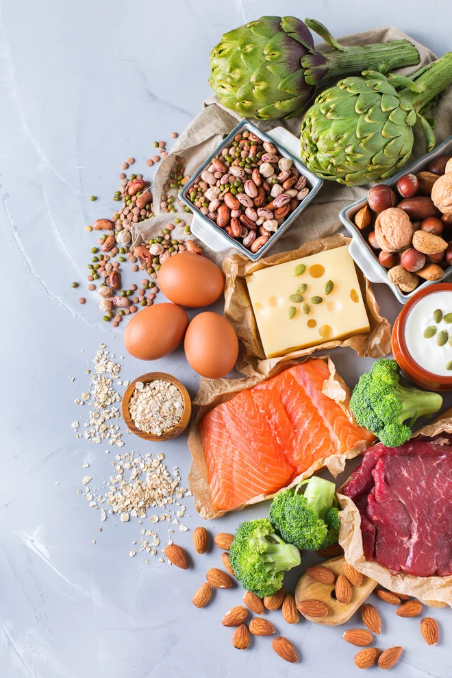 Assortment of healthy protein source and body building food. Meat beef salmon chicken breast eggs dairy products cheese yogurt beans artichokes broccoli nuts oat meal. Copy space background, top view