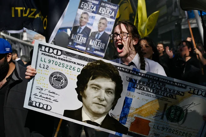 Na predvolilnem shodu v San Martinu v provinci Buenos AiresTiago Codevilla drži velikanski 100-dolarski bankovec z naslikanim obrazom argentinskega kongresnika in predsedniškega kandidata zavezništva La Libertad Avanza Javierja Mileja. Všeč jim je njegov neposredni slog, jeza na politično kasto in pozivi k svobodi. Mladi Argentinci v velikem številu volijo ultraliberalca Javierja Mileija: to je neposredna podpora, ki ne zagotavlja zvestobe, vendar se je za zdaj držijo. Foto: Luis Robayo/Afp