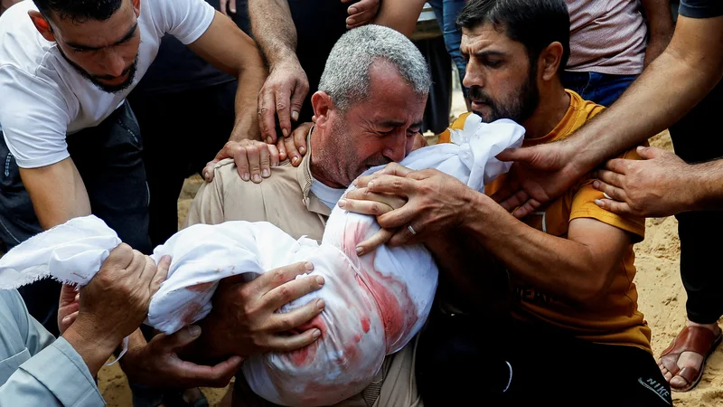 Fotografija: Žalujoči med pokopom trupla palestinskega otroka, ki je bil ubit v izraelskih napadih na južnem območju Gaze. FOTO: Ibrahim Abu Mustafa/Reuters