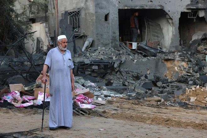 Palestinec ob uničeni zgradbi po sinočnjih napadih na begunsko taborišče v Gazi. FOTO: Said Khatib/AFP