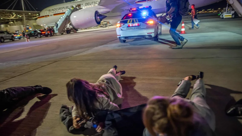 Člani delegacije nemšekga kancelerja Olafa Scholza leže na tleh, medtem ko je kanceler evakuiran. FOTO: Michael Kappeler/AFP