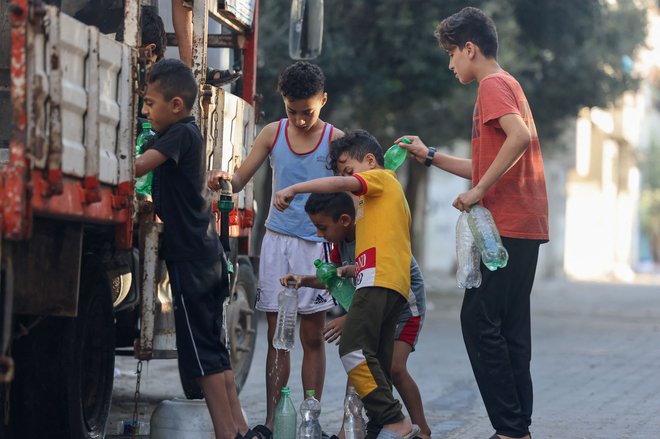 Palestinski dečki v Rafi ob mobilni cisterni z vodo FOTO: Mohammed Abed/AFP