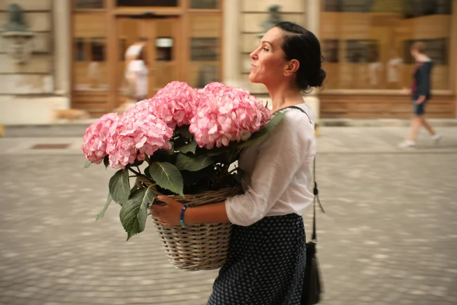 Ženska z rožami na Stritarjevi ulici v Ljubljani junija leta 2016. Fotografija je simbolična. FOTO: Jure Eržen/Delo