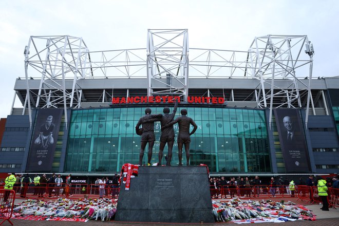 Cvetje ob kipu svete trojice pred Old Traffordom. FOTO: Molly Darlington/Reuters