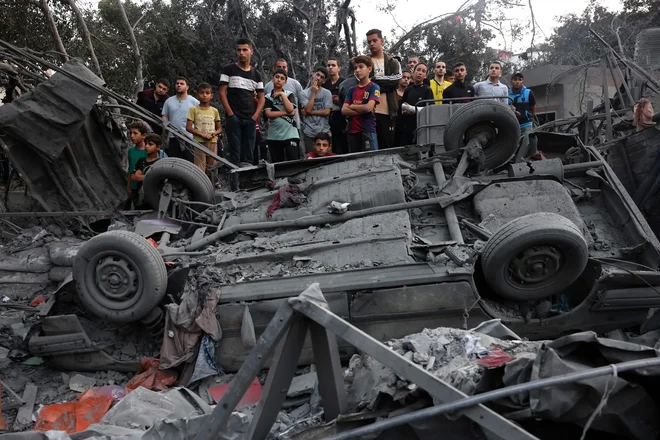 Palestinci opazujejo reševanje izpod ruševin po izraelskem obstreljevanju begunskega taborišča Rafa na jugu Gaze. FOTO: Mohammed Abed/AFP