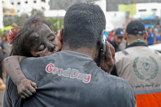Palestinec nosi poškodovano deklico v bolnišnico Al Šifa v Gazi po izraelskih zračnih napadih. Foto: Dawood Nemer/Afp