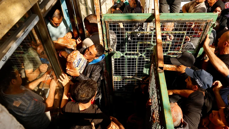 Fotografija: Palestinci čakajo v vrsti na kruh, ki ga v Gazi skupaj z drugimi vrstami hrane močno primanjkuje. FOTO: Ibraheem Abu Mustafa/Reuters