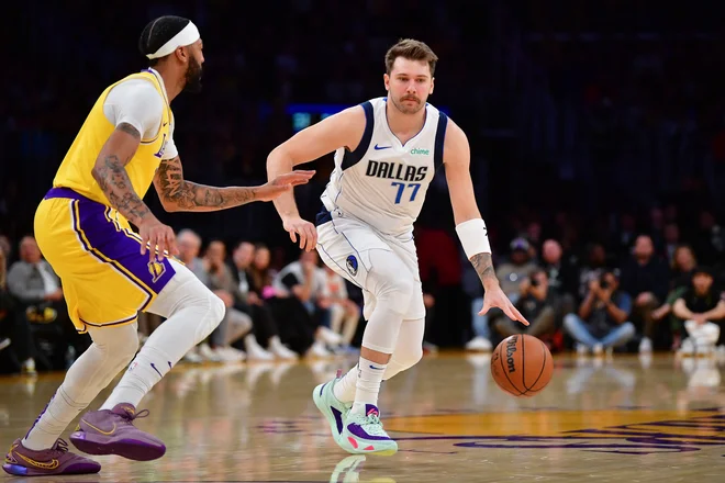 Luka Dončić (z žogo) in adut gostiteljev Anthony Davis med dvobojem. FOTO: Gary A. Vasquez/Usa Today Sports