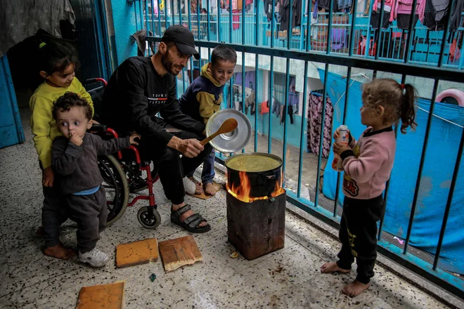 Palestinec kuha v šoli UNWRA, ki jo uporabljajo kot zatočišče v mestu Gaza. FOTO: Omar El Qattaa/AFP