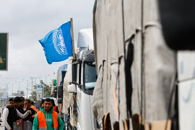 Humanitarno pomoč na meji najprej raztovorijo, nato naložijo blago v tovornjake v organizaciji Združenih narodov, ki ga razvozijo po enklavi. FOTO: Ibraheem Abu Mustafa/Reuters