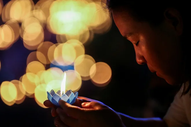 Ženska drži plavajočo košarico iz listov in cvetja, preden jo položi v laguno v parku v Bangkoku med festivalom Loy Krathong, ki poteka kot simbolično opravičilo in zahvala boginji reke za vodo. Foto: Chalinee Thirasupa/Reuters