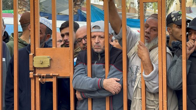 Moški gleda skozi ograjo na ubite Palestince v bolnišnici Nasser. FOTO: Bassam Masoud/Reuters