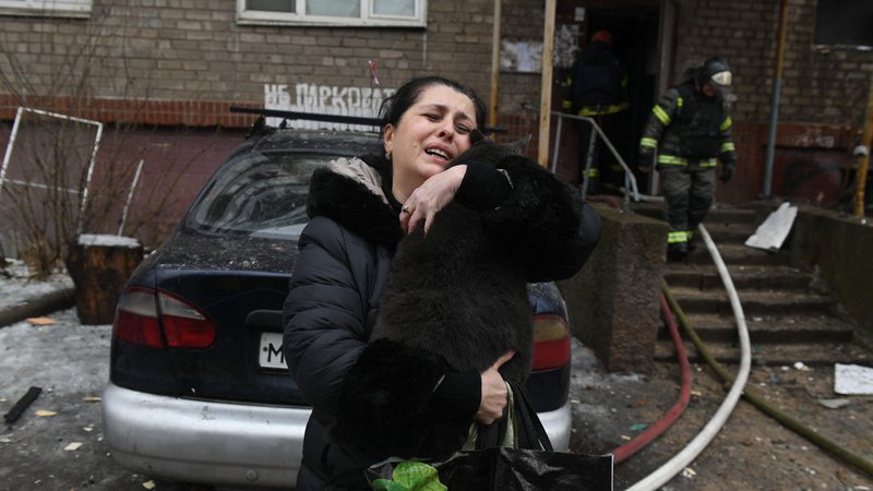Fotografija: Ženska drži svojo mačko, ki so jo gasilci našli v poškodovani večnadstropni stanovanjski stavbi v Donecku, ki je bila včeraj bombardirana s strani ruske vojske. Foto: Stringer/Afp