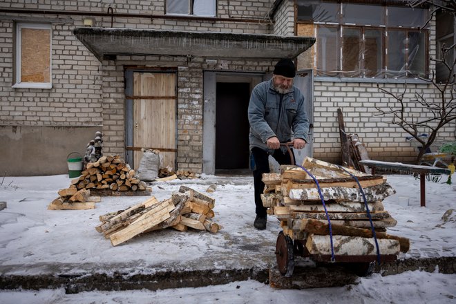 63-letni prebivalec mesta Liman pripravlja drva. Številna mesta so zaradi ruskih napadov brez vode, elektrike in ogrevanja. FOTO: Thomas Peter/Reuters