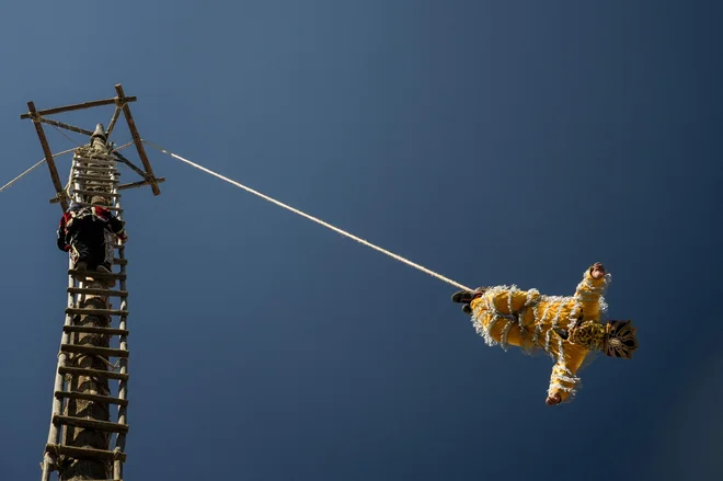 Domorodec izvaja tradicionalni obred pred cerkvijo Santo Tomas v Chichicastenangu v Gvatemali 20. decembra 2023. »Palo volador« (leteči drog) je domorodno-predšpanska tradicija v Gvatemali, pri kateri se ljudje povzpnejo na vrh 30-metrskega debla, da bi se zahvalili za pridelek in pozdravili zimski solsticij. Foto: Emmanuel Andres/Afp