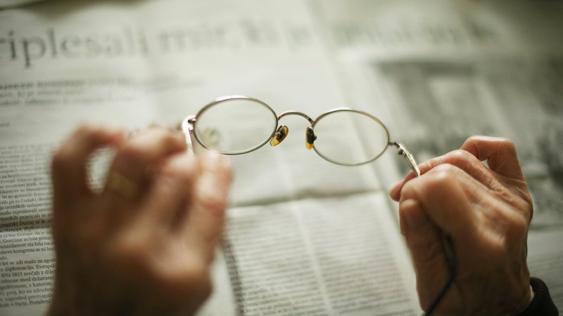 Fotografija: Bralna očala v rokah gospe, ki v centru za starejše občane uživa v branju časopisov. FOTO: Jure Eržen/Delo