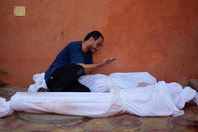 Mohamed Al Ahras ob truplih svoje žene in hčere, ki sta umrli v izraelskih napadih. FOTO: Mohamed Salem/Reuters