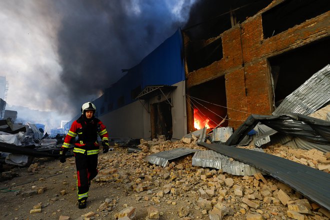 Gasilec med gašenjem stavbe, ki je zagorela po raketnem napadu. FOTO: Valentin Ogirenko/Reuters