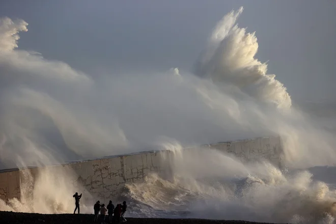 Oseba fotografira valove, ki se lomijo ob valobran v Newhavnu, saj je nevihta Henk prinesla močan veter in obilno deževje v večji del južne Anglije. Foto: Adrian Dennis/Afp