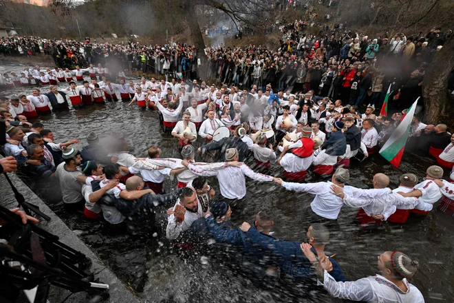 Bolgarski verniki plešejo tradicionalni ples »horo« v reki Tundži v Kaloferju v okviru praznovanja dneva Gospodovega rojstva. Po tradiciji vzhodnopravoslavni duhovnik v reko vrže križ in verjame se, da bo tisti, ki ga bo poiskal, vse leto zdrav, prav tako vsi, ki plešejo v ledeni vodi. Foto: Nikolay Doychinov/Afp