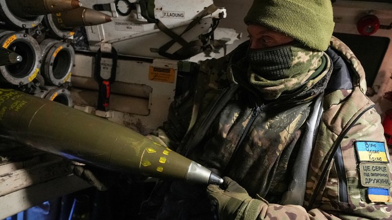 Fotografija: Ukrajinski vojak z izstrelki za havbico kalibra 155 milimetrov v bližini Bahmuta na vzhodu Ukrajine. Ogromne količine tega uničujočega streliva vsak dan padejo na obe strani bojišča, zato povpraševanje po njem ustvarja veliko priložnosti za prekupčevalce. Foto Stringer Reuters