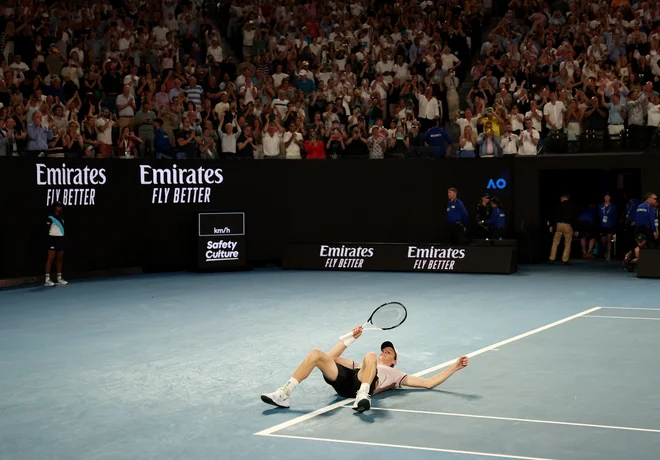 Jannik Sinner se je zgrudil na tla po imenitni zmagi. FOTO: Eloisa Lopez/Reuters