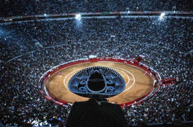 Moški z mehiškim tradicionalnim klobukom mariači gleda bikoborbo na spomeniškem trgu Plaza de Toros Mexico v Mexico Cityju. V Mehiki so se v nedeljo ponovno začele bikoborbe, potem ko je vrhovno sodišče preklicalo prejšnjo prepoved. Foto: Carl De Souza/Afp