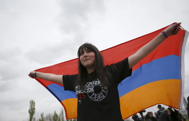 Dekle je 21. aprila 2015 pred muzejem armenskega genocida Tsitsernakaberd razprlo armensko zastavo. FOTO: David Mdzinarishvili/Reuters