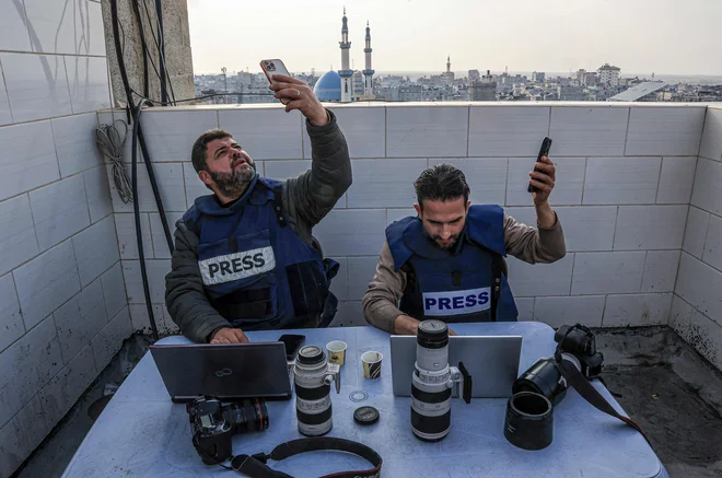 V Rafi na jugu Gaze se palestinski novinarji poskušajo povezati z internetom. Izpadi električne energije so v razdejani Gazi postali vsakdanjost. Vendar lahko Palestinci z vgrajenimi karticami SIM še vedno dostopajo do interneta in ostanejo v stiku s svojimi bližnjimi v tujini. Foto: Said Khatib/Afp
