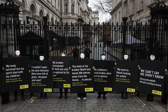 Aktivisti organizacije Amnesty International med tiho vigilijo pred vrati Downing Steet v središču Londona. Pozivajo vlado Združenega kraljestva, naj uporabi vsa razpoložljiva sredstva in pritisne na izraelske oblasti, da prekličejo odločitev o napadu na Rafo. Ministrstvo za zdravje v Gazi, je sporočilo, da je bilo na tem ozemlju ubitih najmanj 28 576 ljudi. Vojno je sprožil Hamasov napad na Izrael 7. oktobra, v katerem je umrlo približno 1.160 ljudi. Od 250 talcev, ki jih je Hamas zajel med napadom 7. oktobra, naj bi jih bilo v Gazi še vedno približno 130. Izrael pravi, da jih je 29 domnevno mrtvih. Foto: Daniel Leal/Afp
