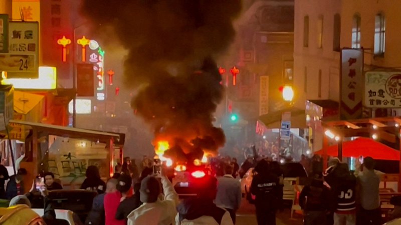 Fotografija: Waymov robotski taksi v ognju sredi San Francisca, potem ko so ga neznani storilci razbili in vanj metali rakete. FOTO: Michael Vandi/Reuters