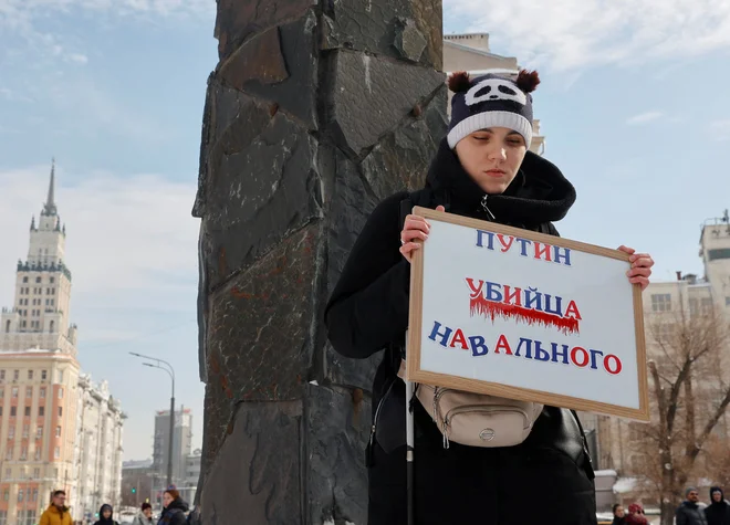 Ženska s transparentom »Putin je moriec Navalnega« na današnji fotografiji, posneti v bližini spomenika žrtvam politične represije v Moskvi. FOTO: Reuters