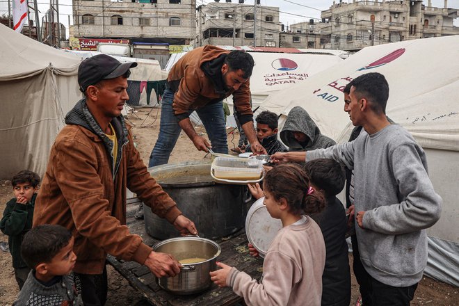 Prostovoljci v Rafi razdeljujejo hrano. Po več kot štirih mesecih spopadov prebivalce Gaze ogroža lakota. FOTO: Said Khatib/AFP