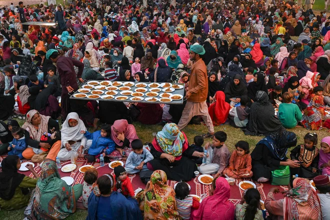 Prostovoljci delijo brezplačno hrano, medtem ko se muslimanski verniki zbirajo, da bi prekinili post med islamskim svetim mesecem ramadan v Lahoreju. Foto: Arif Ali/Afp